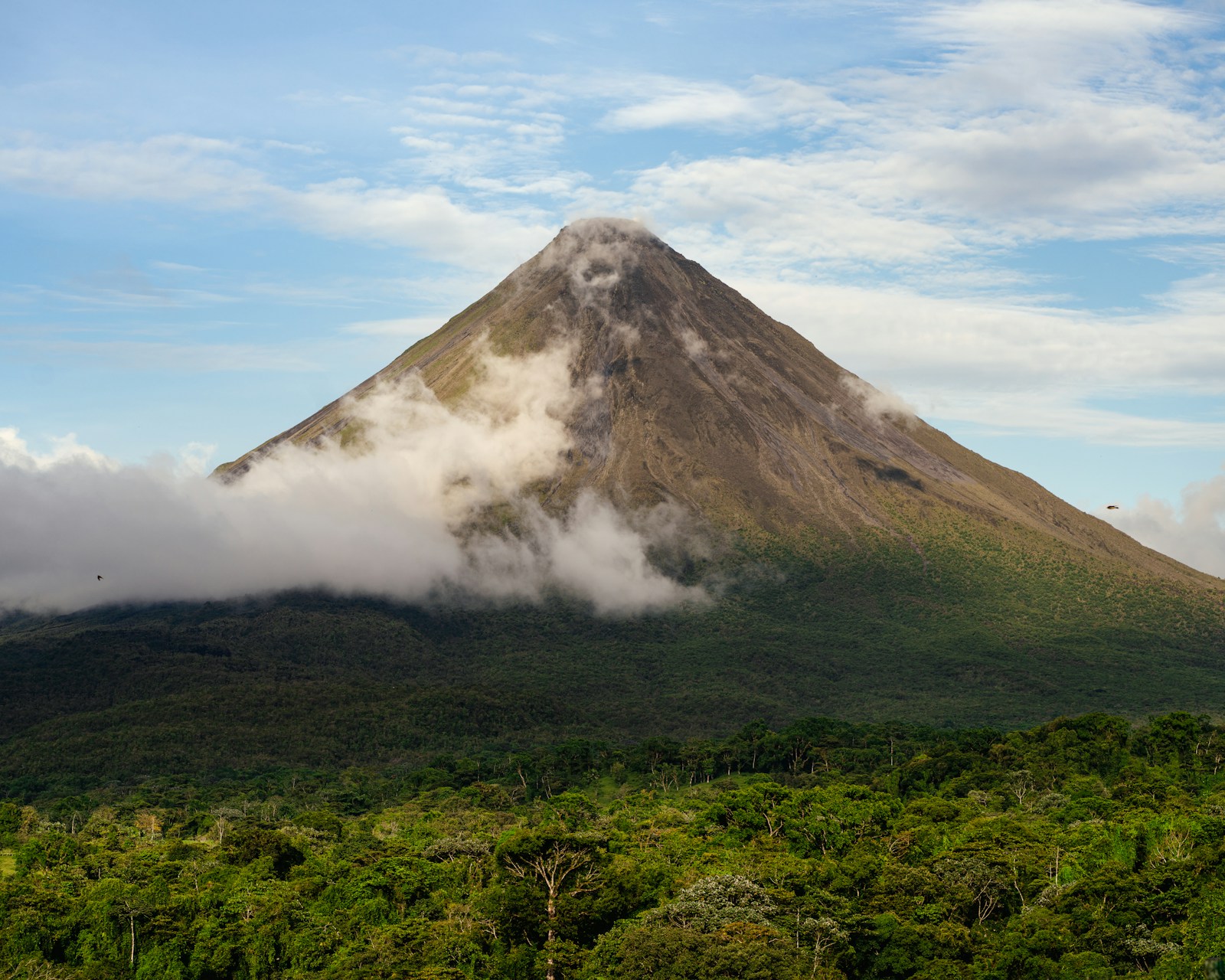 Arenal volcano rising above lush green rainforest