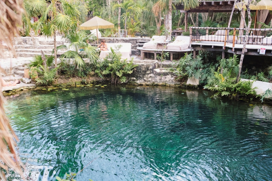 Turquoise cenote ringed by palms and umbrellas