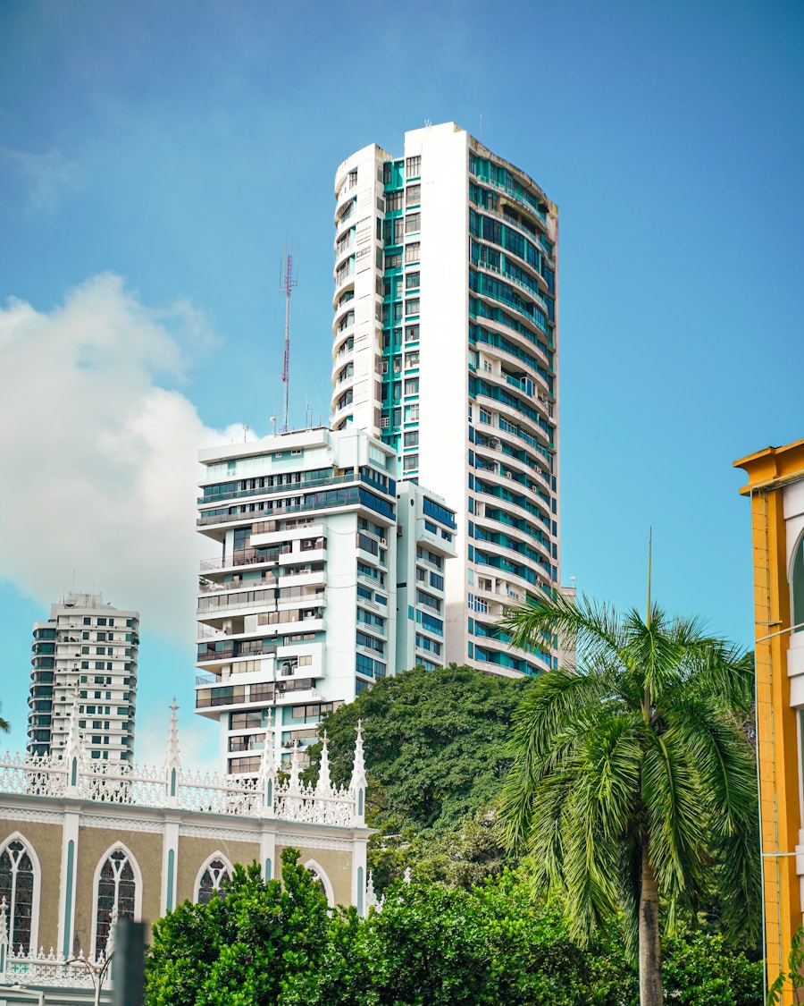 Modern white residential tower rising beside lush forest