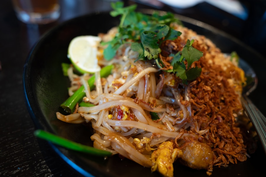 Plate of Thai pad thai noodles with fresh herbs and lime