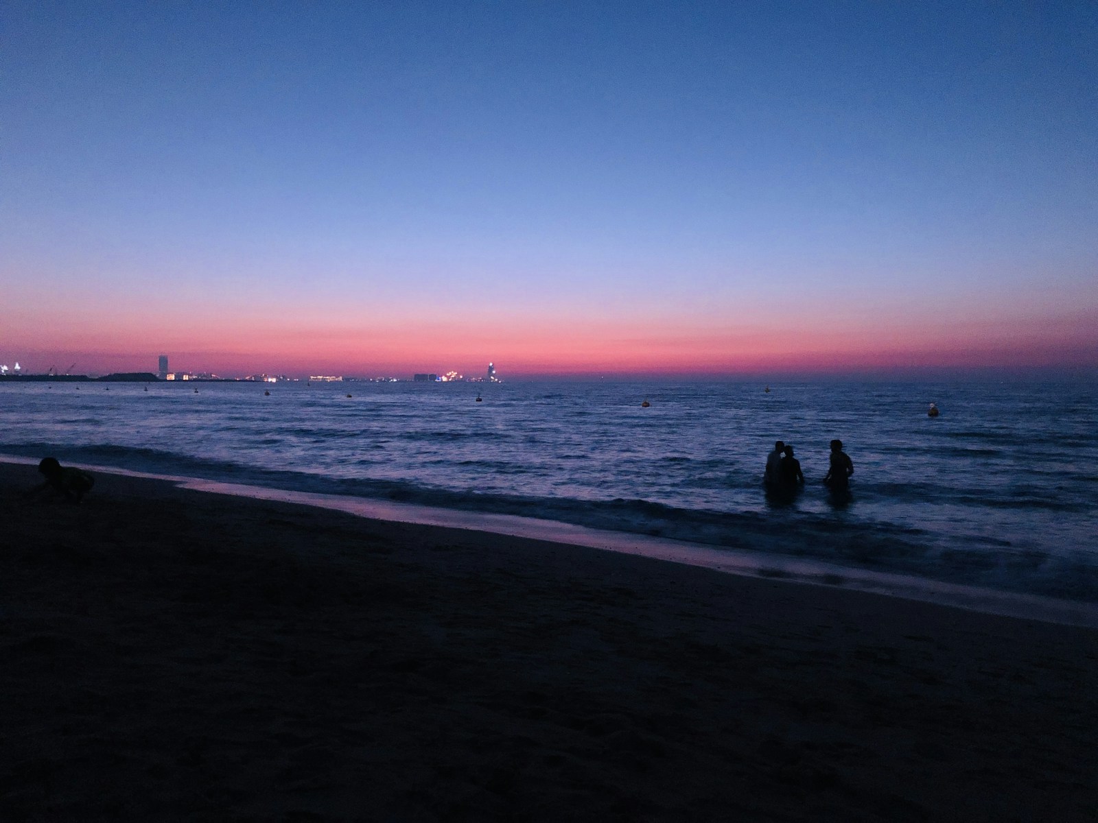 Two silhouettes walking on a Jumeirah beach at sunset