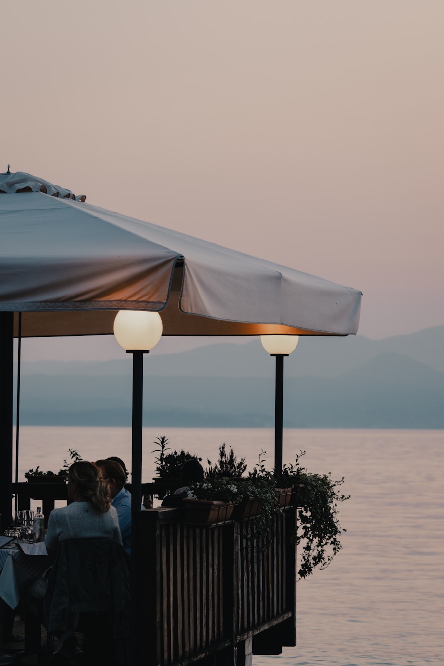 Diners on a restaurant terrace by the water at dusk
